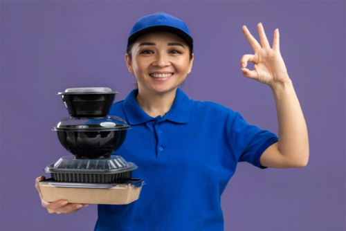 cheerful delivery woman with various food packaging